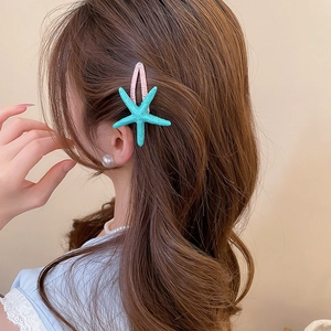 Close-up of a mint green starfish hair clip with pink glitter on wavy brown hair
