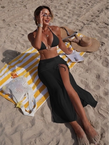 Three-piece black bikini set with gold ring detail and matching side-slit beach cover-up skirt
