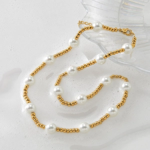 Elegant white pearl and gold bead necklace with lobster clasp on a bubbly foam background