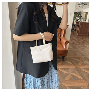 Photo lifestyle d'un petit sac seau blanc en nylon porté avec une robe à fleurs