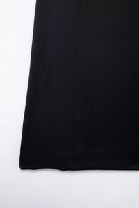 Primer plano detallado del dobladillo de tela negra suave con brillo sutil en vestido