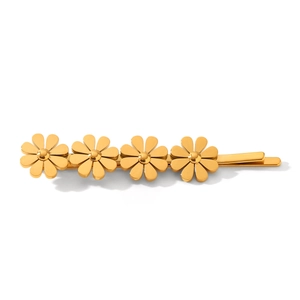Détail d'une pince à cheveux marguerite dorée avec quatre fleurs métalliques sur barre plate