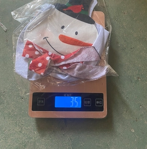 Detail showing a 35g Christmas snowman gift bag being weighed on a digital scale