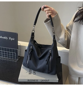 Detail of black lychee grain leather tote bag featuring stylish side vertical zippers