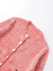 Close-up of red and white chunky knit fabric with decorative gold round buttons