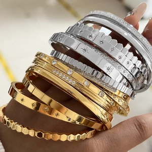 Detailed view of stacked gold and silver stainless steel bangles with star patterns