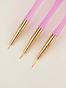 Macro shot of three pink acrylic nail art liners with fine synthetic bristles and gold tubes