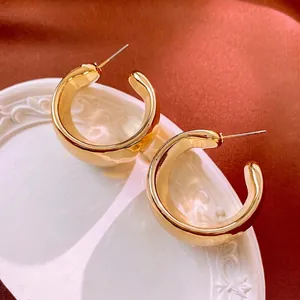 Minimalist wide C-shape gold chunky hoop earrings on elegant ceramic plate