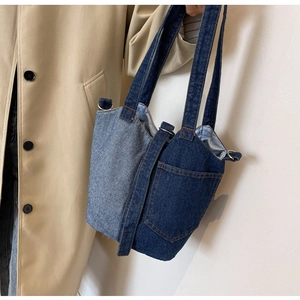Detail of blue denim bucket bag with patchwork design and practical front pocket
