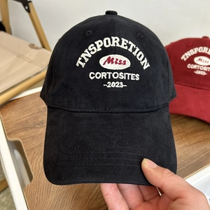Black cotton baseball cap with intricate embroidery on a light wooden background