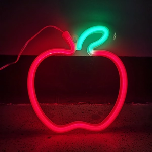 Detail of red apple neon sign with green leaf for festive wall decoration