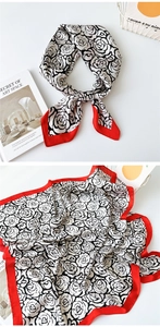 Detail of silk square scarf featuring black white rose print and bold red border accent