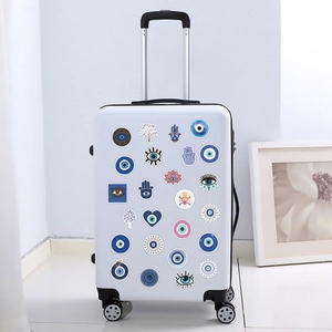 Blue Evil Eye and Hamsa Hand stickers applied on a white suitcase for decoration