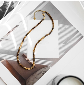Detailed view of vintage tiger eye beaded necklace with gold square accents on book
