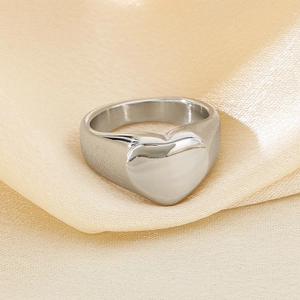 Detailed view of silver heart signet ring on textured champagne satin fabric