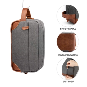 Detail view of a mens canvas toiletry bag showing handle, bottom, and zipper features.