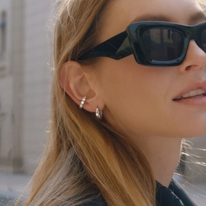 Silver zircon ear cuff and hoop earring set worn by a model in an outdoor setting