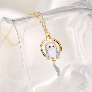 Golden necklace featuring a round pendant with a white striped enamel cat and blue eyes