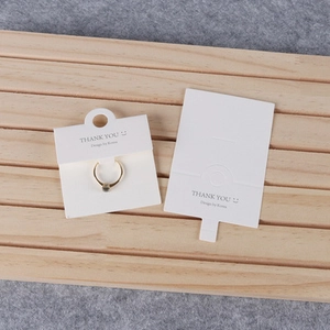 Close-up of white jewelry ring display cards with Thank You text on wooden tray