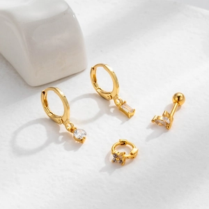 Detail of four gold-plated ear studs and hoops set with clear sparkling crystals