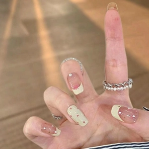 Sweet French press-on nails with green polka dots, pink base, and rhinestone bows
