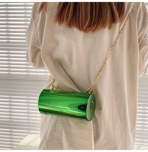 Detail shot of a green acrylic cylinder chain bag worn over a beige shirt