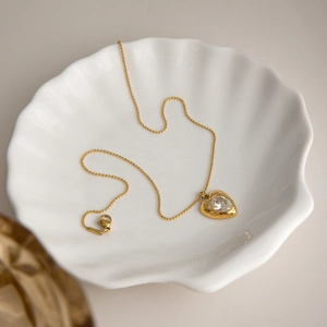 Collier élégant avec pendentif cœur doré et zircon rond sur plateau coquillage blanc