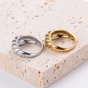 Polished 18K gold and silver stainless steel croissant rings on a stone base