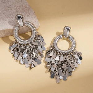 Boucles d'oreilles argentées texturées avec pampilles à paillettes sur fond de pierre