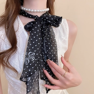 Detail of black polka dot silk scarf necklace with elegant white pearls and rose patterns