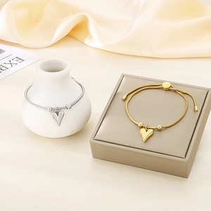 Elegant 18K gold and silver heart snake chain bracelets displayed on silk
