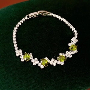 Detail view of olive green oval zircon stones on silver geometric buckle bracelet
