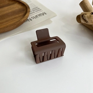 Close-up of square matte brown hair claw clip on a stylish table with aesthetic decor