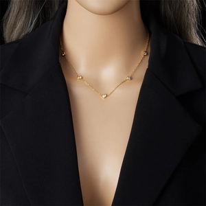 Elegant gold stainless steel necklace featuring heart pendants with clear stones on a model