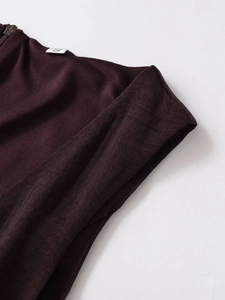 Detalle de vestido marrón oscuro con etiqueta talla S, cremallera y textura de tela tejida