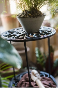 Détail d'un support de plante en fonte noire avec des motifs ajourés vintage
