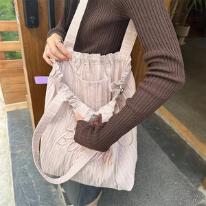 Detail of pink striped canvas tote bag featuring Bonne embroidery and drawstring closure
