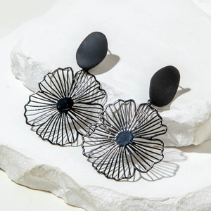 Gros plan sur des boucles d'oreilles feuille noir mat avec pétales en métal ajouré