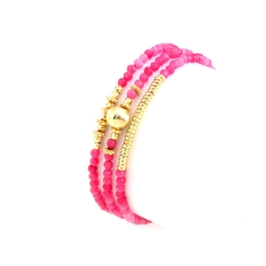 Macro shot of layered fuchsia carnelian beads and gold-plated spacers on a sleek bracelet