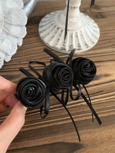 Détail d'une pince à cheveux rose en satin noir faite main avec des rubans vintage