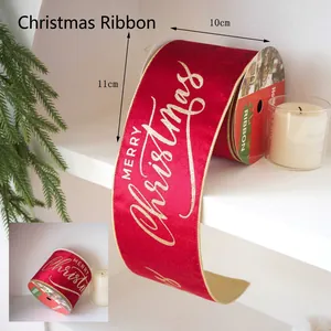 Macro detail of red velvet Christmas ribbon featuring gold Merry Christmas typography