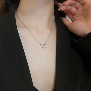 Close-up of minimalist silver zircon circle necklace worn with a black blazer for elegance
