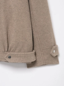 Detail of wool fabric texture, metal buttons and stitching on camel bomber jacket