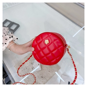 Detail of red quilted round crossbody bag for girls featuring a golden camellia floral ornament