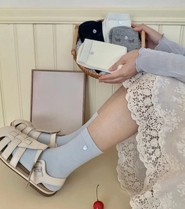 Détail de chaussettes en coton côtelé avec bouton décoratif en plusieurs tons pastels