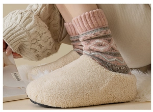 Close-up of pink knitted wool socks with plush beige slippers for cozy winter comfort