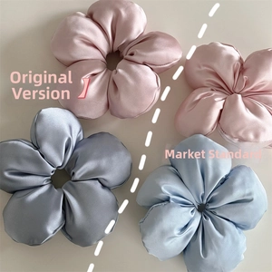 Close-up of three-dimensional satin flower hair ties in soft pink and grey-blue tones