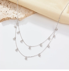Detail of a double-layered 925 silver necklace with small zircons on a rustic stone background