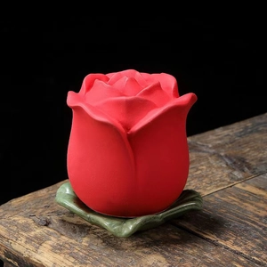 Mini contenitore da tè in ceramica a forma di bocciolo di rosa rossa su tavolo rustico