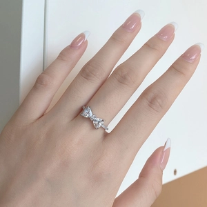 Close-up of heart-cut stones bow ring in S925 sterling silver on woman's finger